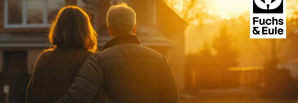 Zwei Personen vor ihrem Haus im Sonnenuntergang.